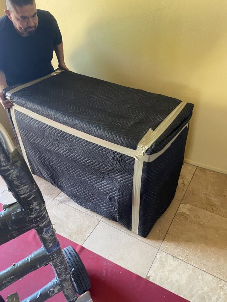 A professional mover carefully transporting wrapped furniture on a dolly for Moving Marvels in Tucson, AZ.