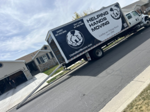 A Helping Hands Moving & Maids truck with an extended ramp at a residential home, indicating a moving job in Salt Lake City, UT.