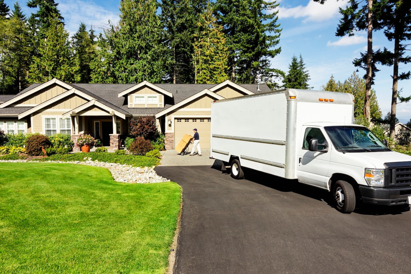 A mover unloading a box from a truck with a dolly in front of a house for Central Movers, Inc. in Annapolis, MD.