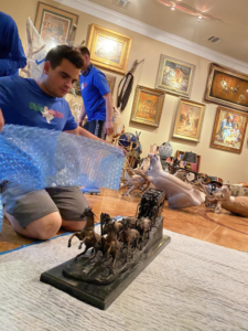 A professional mover from Antz Movers Company in Austin, TX, carefully placing a decorative item onto a shelf during an unpacking service.