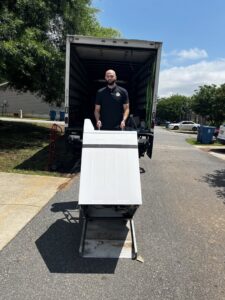 A mover carefully unloading a washing machine from a truck for Rambling Man Logistics in Hildebran, NC.