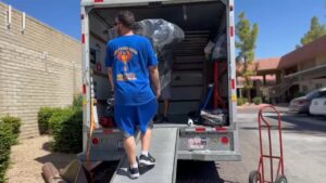 A mover from Rising Phoenix Movers LLC walking up a ramp into a moving truck during a service in Phoenix, AZ.