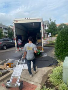 A mover from Gifted Hands Moving & Storage in Collierville, TN, with a dolly near a moving truck and extended ramp.