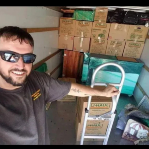 A friendly mover from Rising Phoenix Movers LLC with a hand truck inside a packed moving truck in Phoenix, AZ.