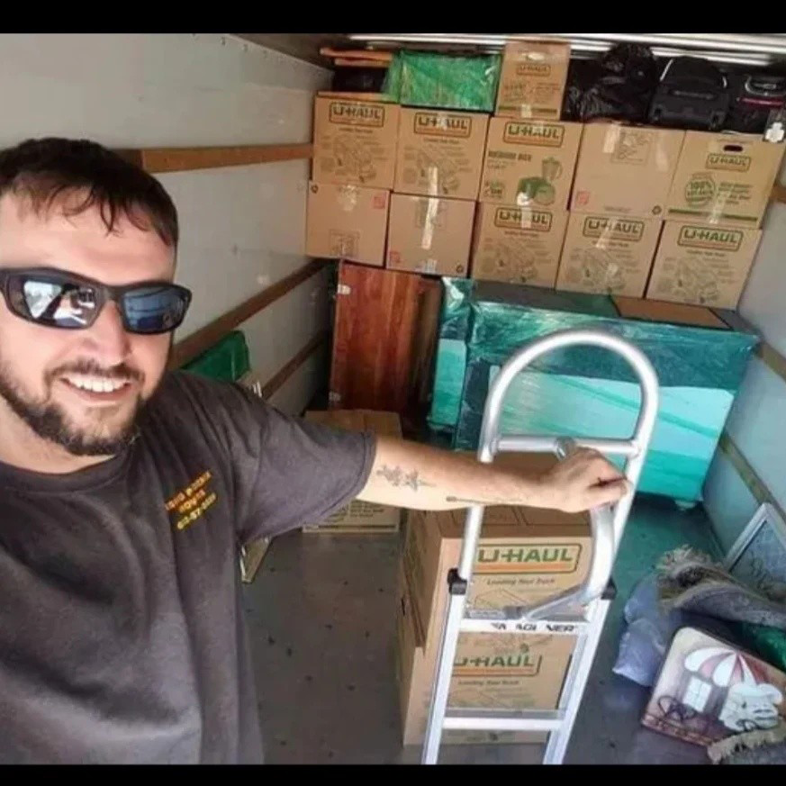 A friendly mover from Rising Phoenix Movers LLC with a hand truck inside a packed moving truck in Phoenix, AZ.