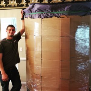A mover standing next to a large, carefully wrapped and boxed item, ready for transport by S&P Network's Marathon Moving Solutions in Mechanicsburg, PA.