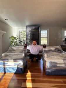 A mover from Paradise Moving & Storage standing with wrapped furniture inside a house in Boston, MA.