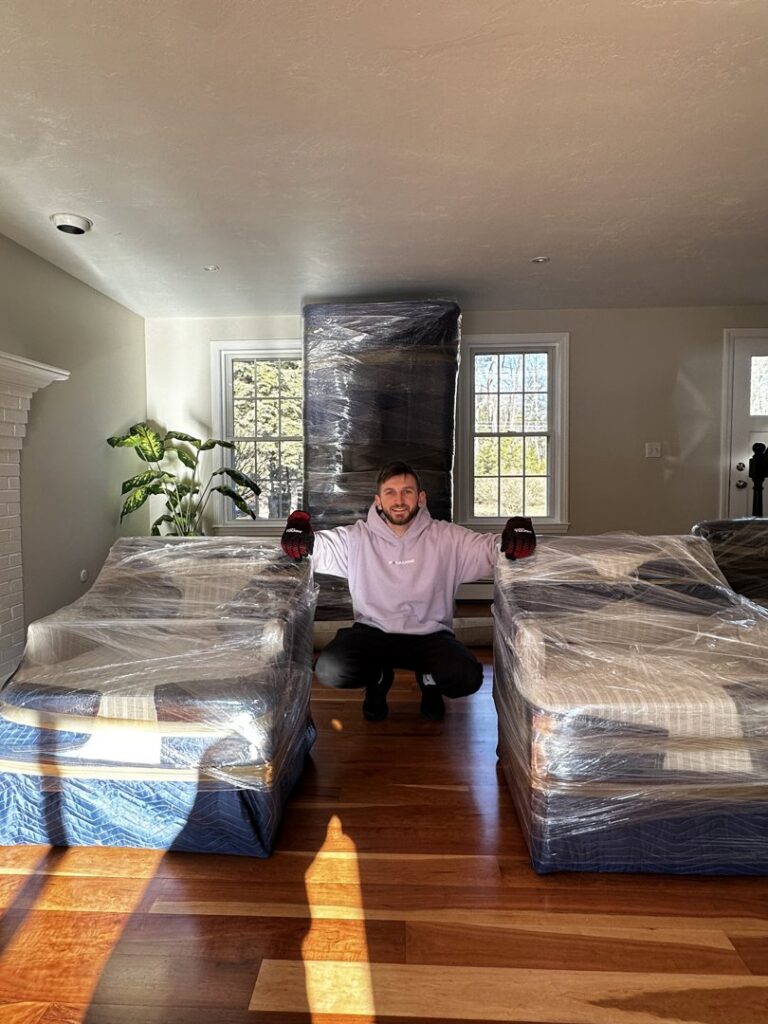A mover from Paradise Moving & Storage standing with wrapped furniture inside a house in Boston, MA.