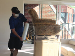 A mover carefully wrapping an armchair with plastic for Coakley Brothers & Brothers Interiors in Milwaukee, WI.