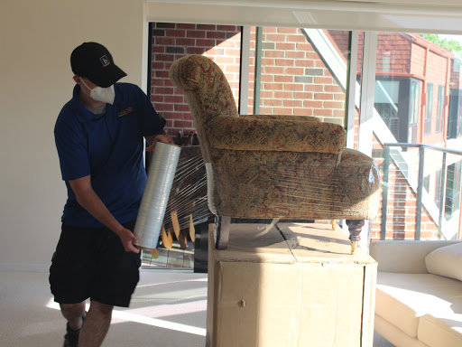 A mover carefully wrapping an armchair with plastic for Coakley Brothers & Brothers Interiors in Milwaukee, WI.