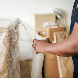 A mover carefully wrapping furniture with plastic for protection at Delivery on Demand in Scottsdale, AZ