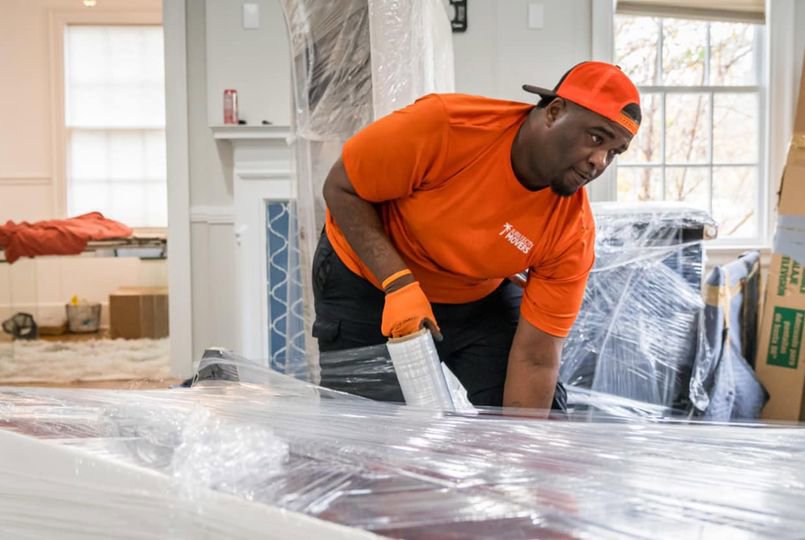 A Jubilee City Movers team member carefully wrapping furniture with plastic for protection in Montgomery, AL.