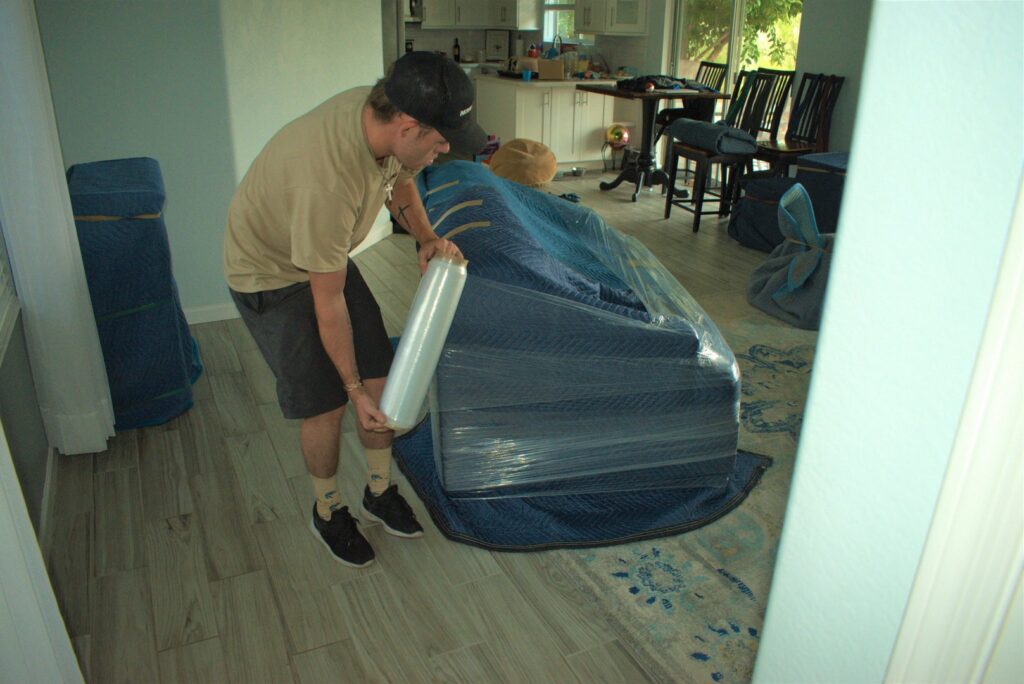 A professional mover wrapping furniture with plastic wrap for protection by Moving Pros LLC in Surprise, AZ.