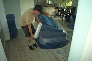 A professional mover wrapping furniture with plastic wrap for protection by Moving Pros LLC in Surprise, AZ.