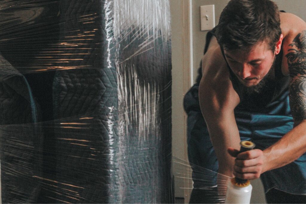 An Ingenuity Moving team member wrapping a large piece of furniture for protection in Kansas City, MO.