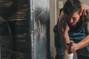 An Ingenuity Moving team member wrapping a large piece of furniture for protection in Kansas City, MO.