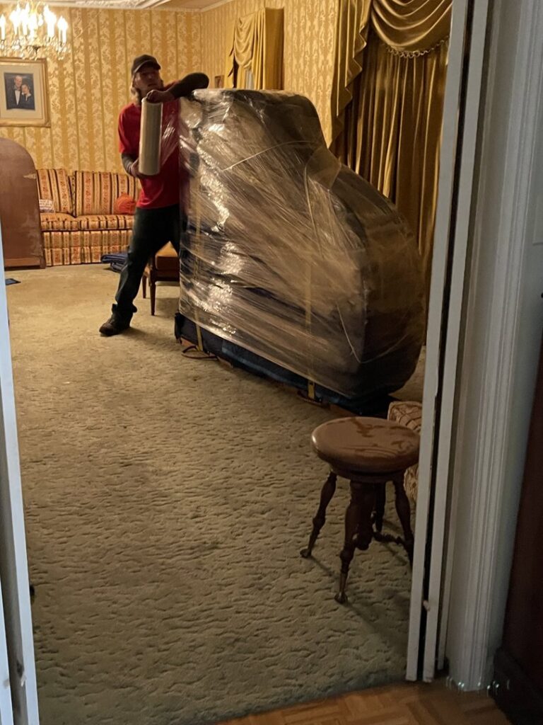 A professional mover carefully wrapping a piano for safe transport by Peroulas Moving and Storage in Knoxville, TN