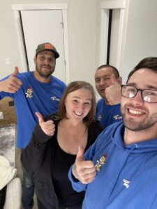 Movers and a happy customer giving thumbs up inside a home after a successful move by Let's Get Moving in Saint Petersburg, FL.