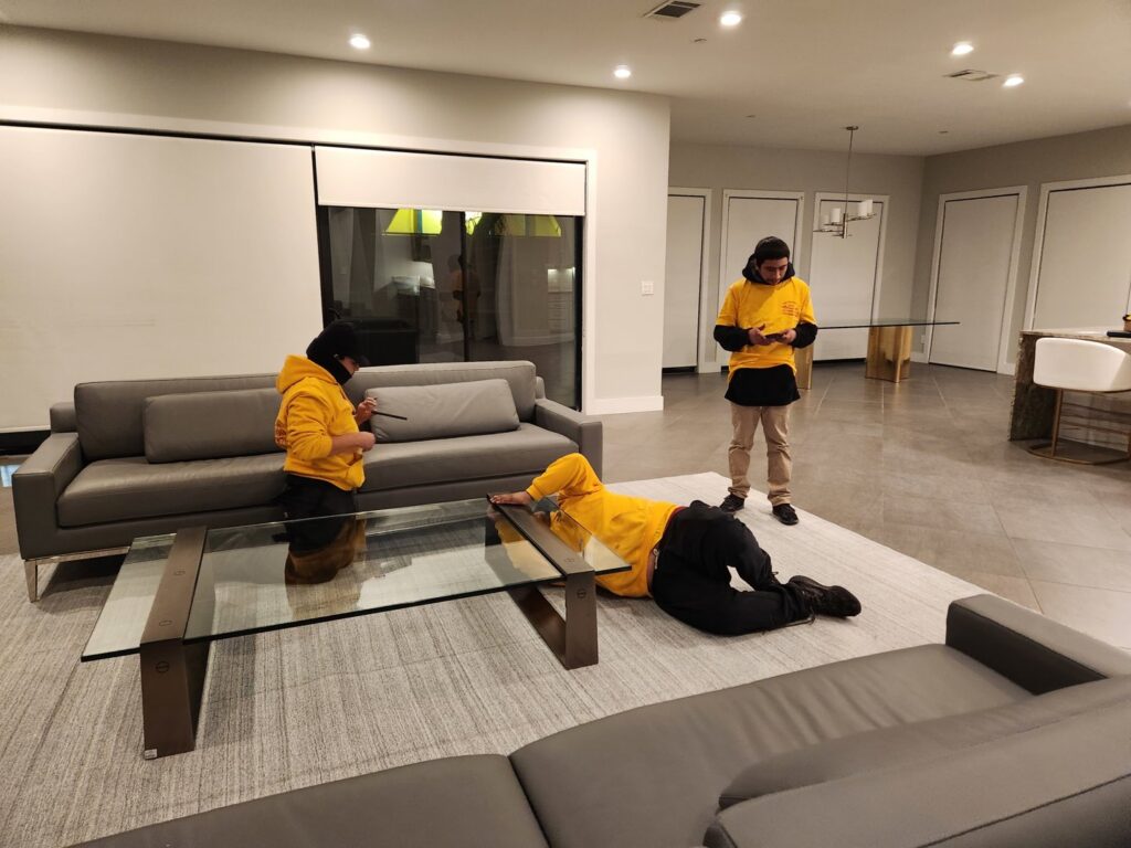 Ang Moving Co movers assembling a glass coffee table in a modern living room in Dallas, TX