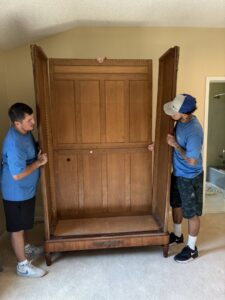 Two movers from Reynolds Moving in Baton Rouge, LA, working together to assemble a large wooden cabinet
