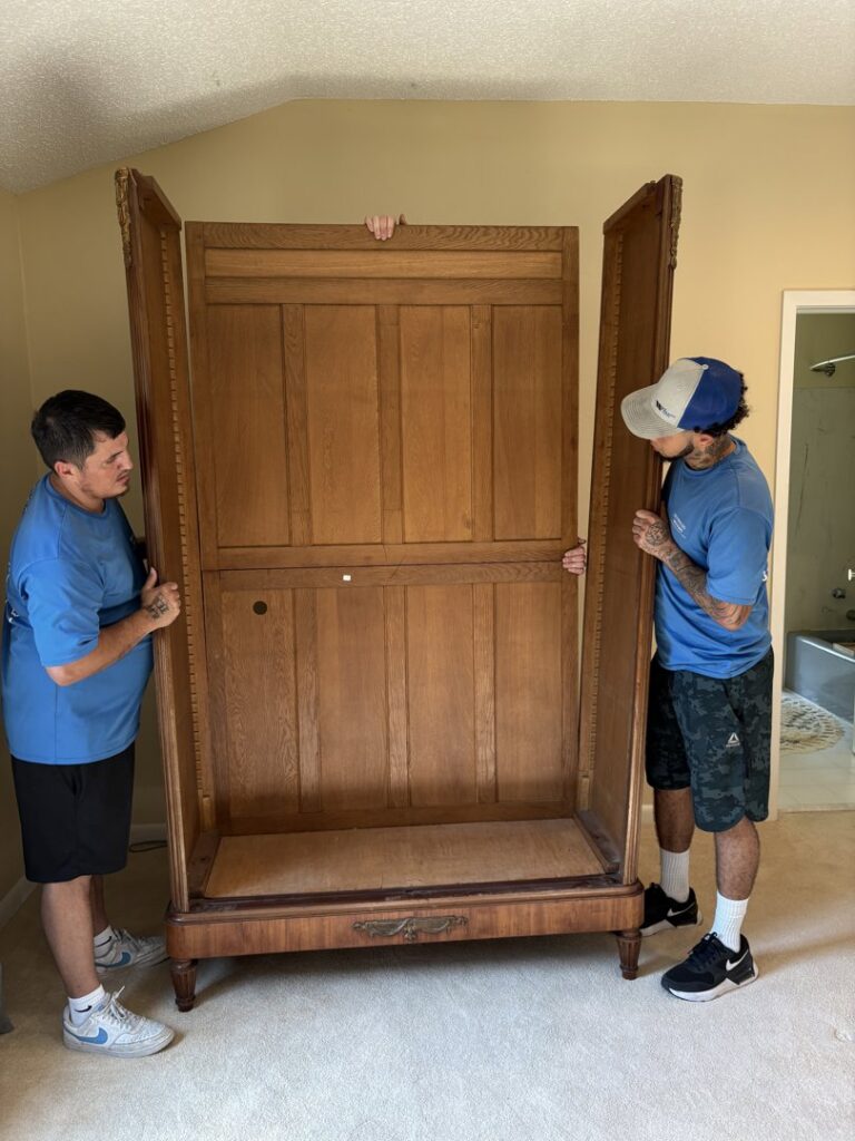 Two movers from Reynolds Moving in Baton Rouge, LA, working together to assemble a large wooden cabinet