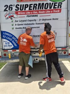 Two Jubilee City Movers team members preparing to load or unload items at the back of a moving truck in Montgomery, AL.