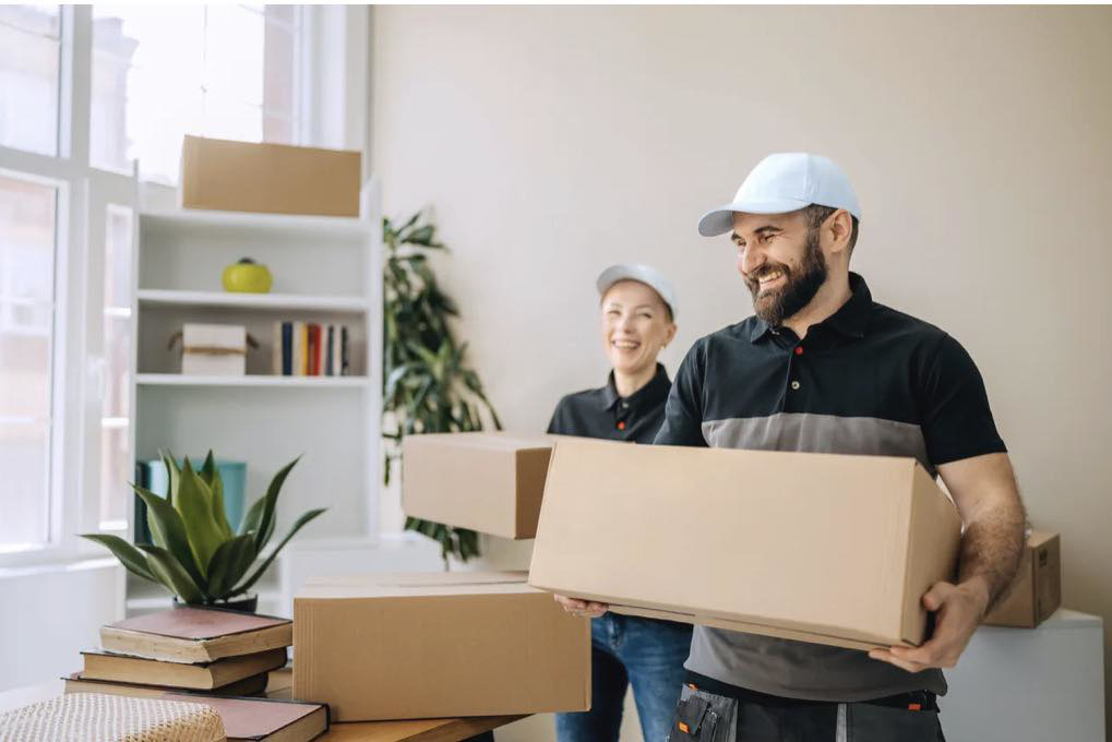 Two professional movers from Helping Hands Moving & Maids carrying boxes inside a home in Salt Lake City, UT.