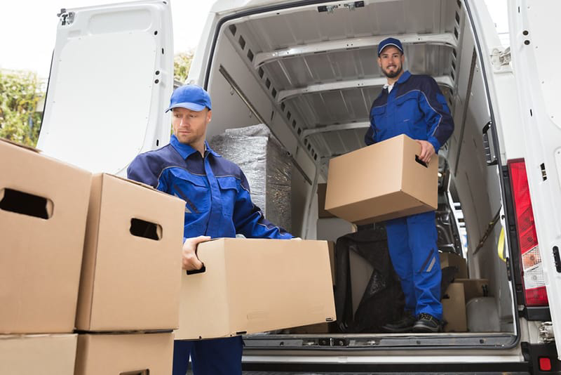 Two professional movers carrying cardboard boxes to a moving van at All Around Town Movers in Memphis, TN.