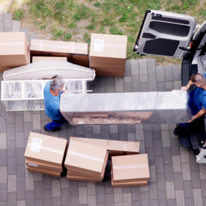 Two professional movers carrying wrapped furniture into a moving van for Blue Sky Moving in Fort Lauderdale, FL