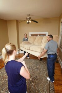 Two professional movers from Leaders Moving & Storage Co. carrying a sofa inside a home in Indianapolis, IN.