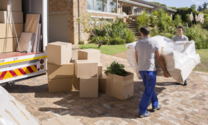 Two professional movers carrying a sofa to a moving truck with boxes at All Around Town Movers in Memphis, TN.