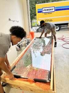 Two movers from Gifted Journey Movers carefully crating a large piece of artwork for safe transport in Gulfport, MS.