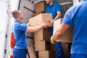 Three professional movers from Three Movers in Henderson, NV, loading cardboard boxes into a moving van.
