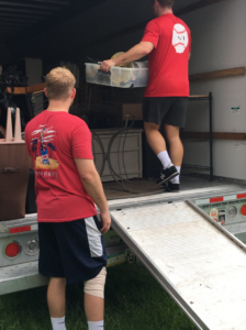 Professional movers from Natural State Moving loading household items into a truck with a ramp in Conway, AR.