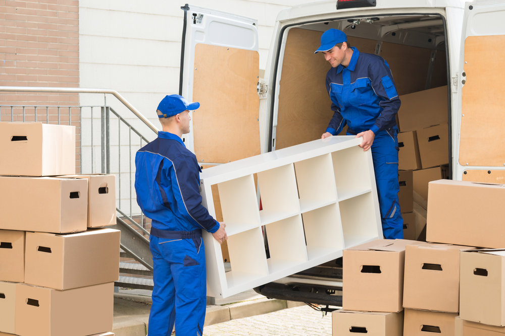 Two professional movers from Three Movers in Henderson, NV, carefully loading a shelving unit into a moving van.