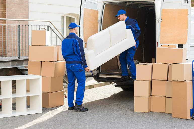 Two professional movers carefully loading a sofa into a moving van at All Around Town Movers in Memphis, TN.