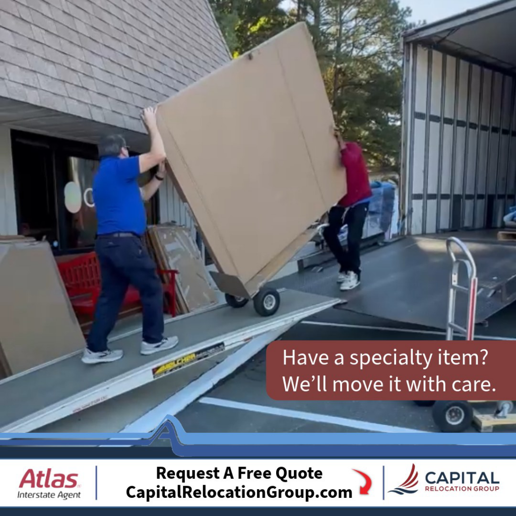 Movers carefully loading a large, wrapped specialty item onto a moving truck for Capital Relocation Group in Raleigh, NC.