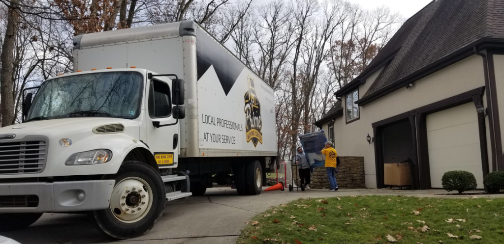 Professional movers loading items onto a Prime Moving Center truck outside a home in Pittsburgh, PA.