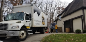 Professional movers loading items onto a Prime Moving Center truck outside a home in Pittsburgh, PA.