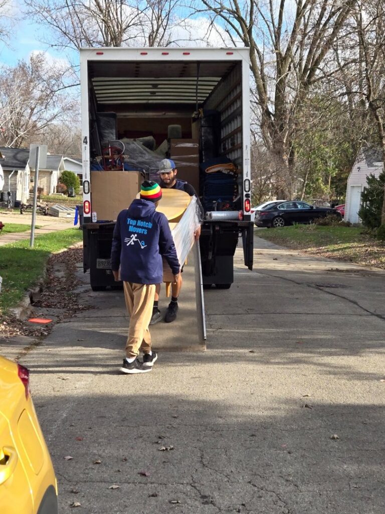 Two Top Notch Movers employees loading items onto a moving truck using a ramp in Lauderhill, FL.