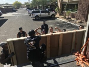 Muscular Moving Men & Storage movers loading a large wooden panel onto a moving truck in Phoenix, AZ.
