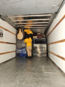 Ang Moving Co movers loading wrapped furniture and boxes into a moving truck in Dallas, TX