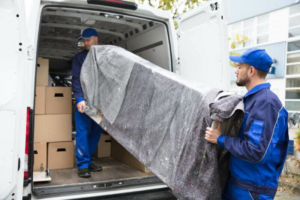 Movers from 4D Extreme Movers loading a wrapped sofa into a moving van with boxes in Atlanta, GA.