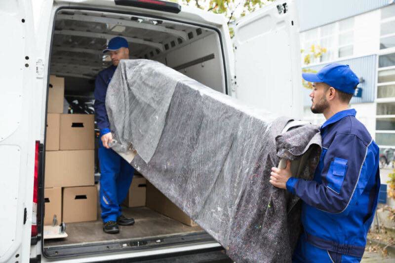 Movers from 4D Extreme Movers loading a wrapped sofa into a moving van with boxes in Atlanta, GA.
