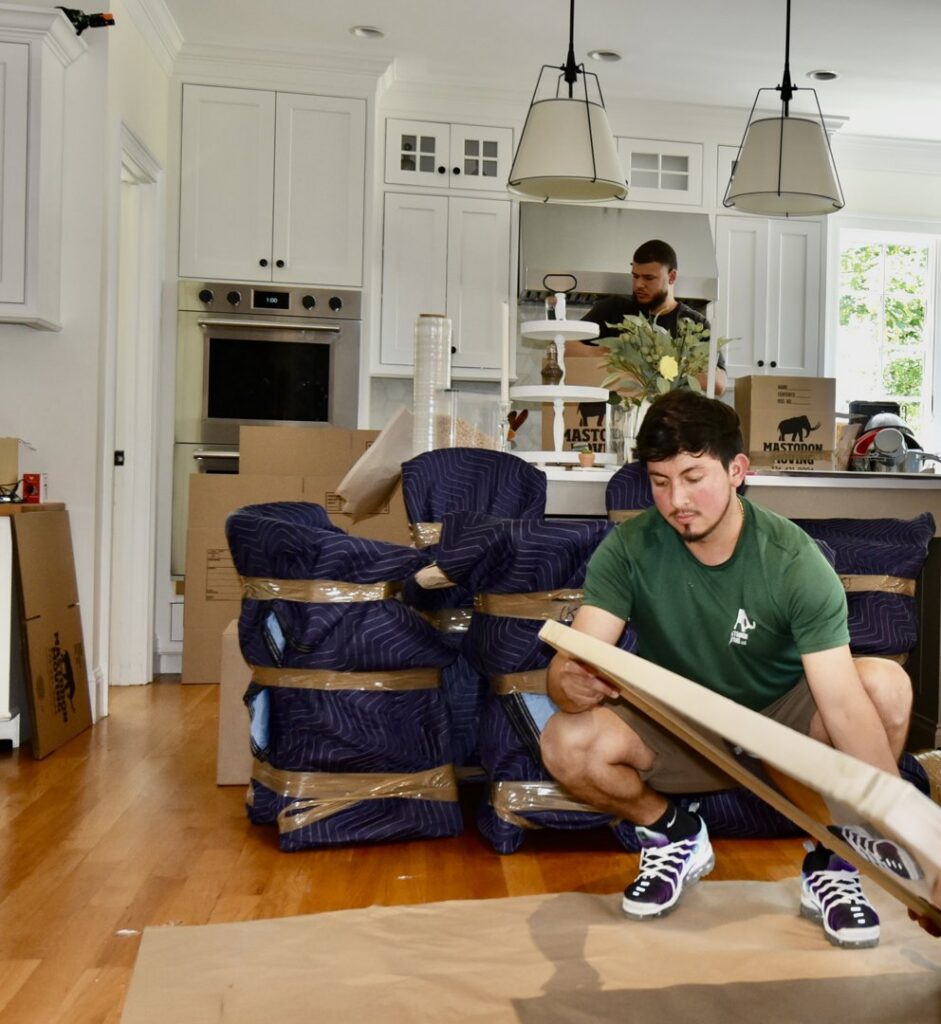 Two Mastodon Moving LLC movers carefully packing items in a kitchen in Westborough, MA.