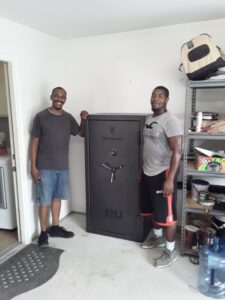 Two movers from allpromovingservice standing next to a heavy safe they are relocating in San Antonio, TX.