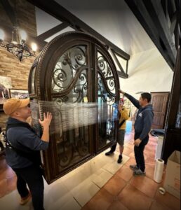 Prime Moving professionals carefully relocating a large, ornate door wrapped for protection in Boston, MA.
