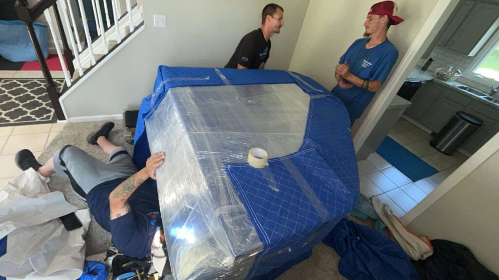 Move Moore team members relocating a large, padded item inside a client's home in Grand Rapids, MI.
