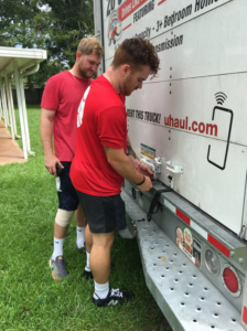 Two movers from Natural State Moving securing items on a U-Haul truck in Conway, AR, ensuring safe transport.