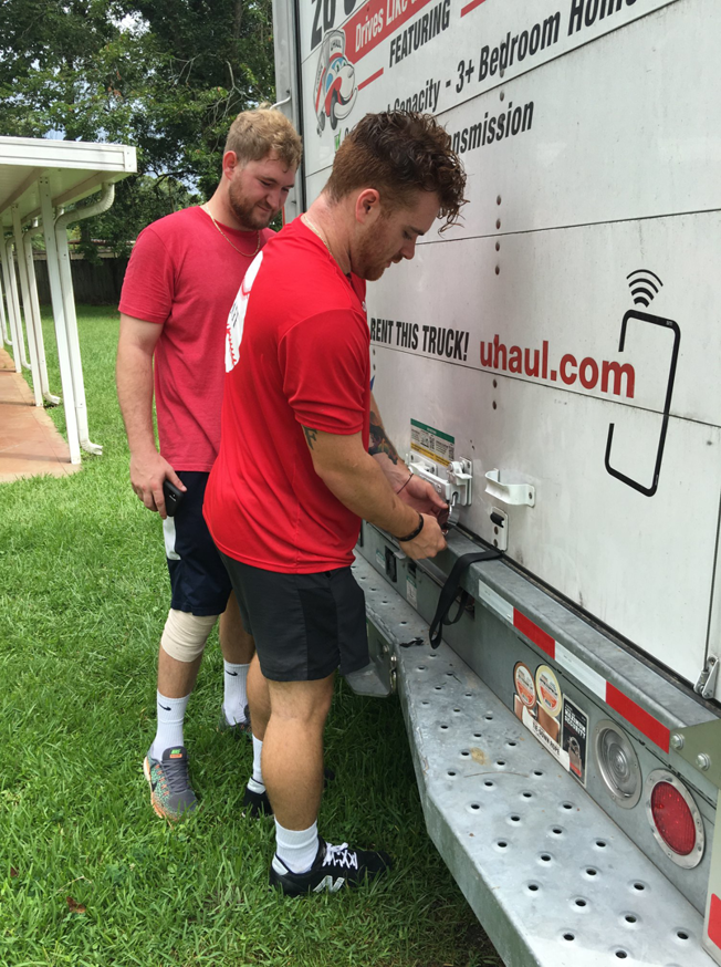 Two movers from Natural State Moving securing items on a U-Haul truck in Conway, AR, ensuring safe transport.